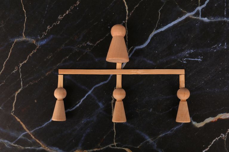 Artistic minimalist wooden balancing scale on dark marble surface, showcasing symmetry.