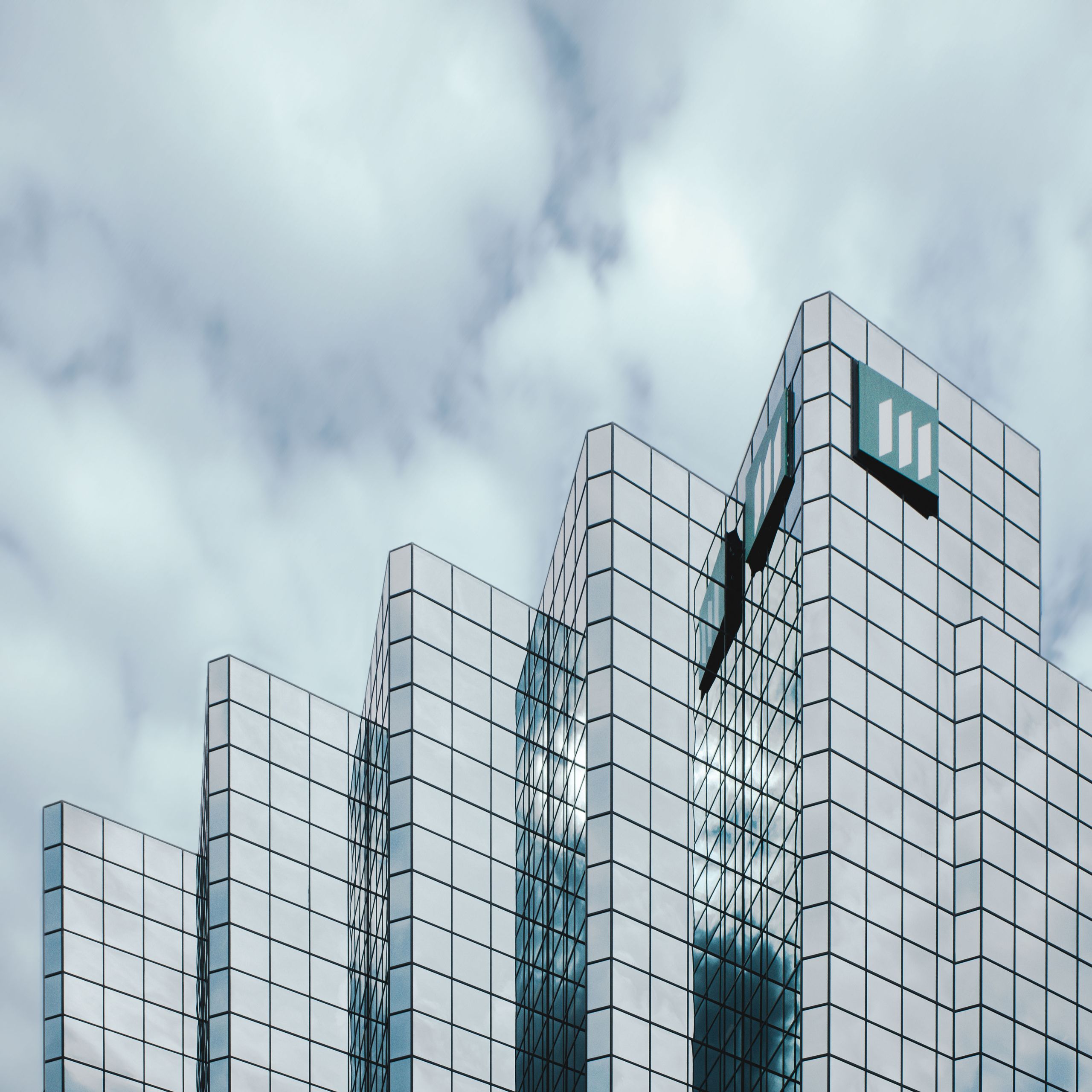 Contemporary skyscraper with mirrored glass reflecting clouds, showcasing urban architecture.